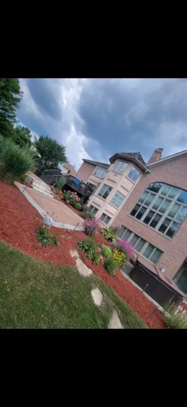 Large brick home with red mulch flower beds and colorful plantings