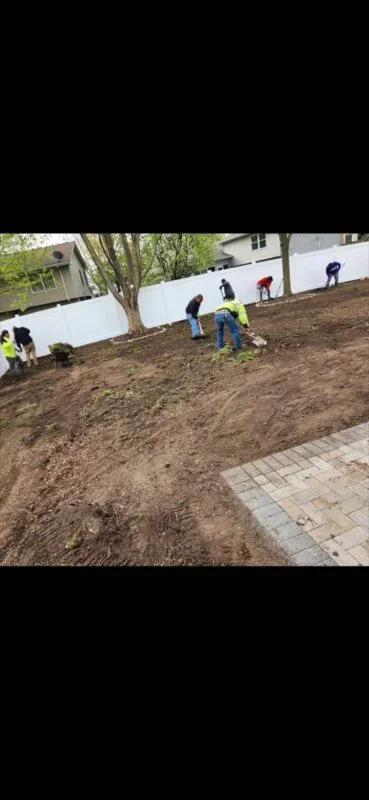 Landscaping crew working on yard preparation with fence and pavers