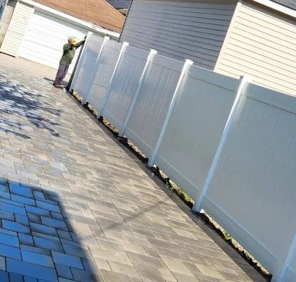 White vinyl privacy fence installation on brick paver surface