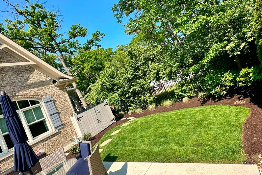 Backyard lawn care and mulch bed installation with mature trees