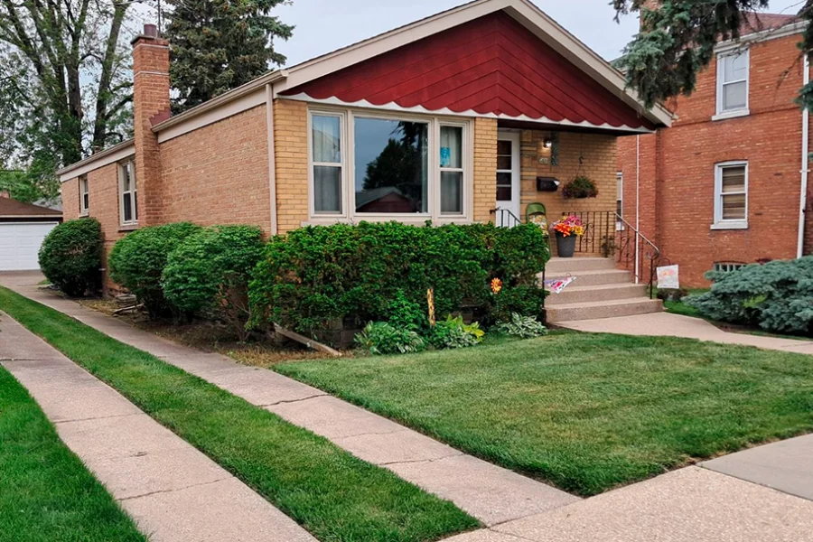 Residential lawn maintenance with trimmed hedges in front of brick home